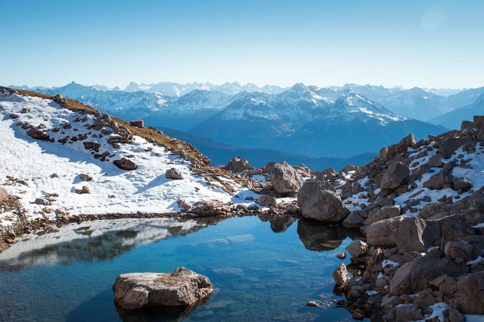 Lac de montagne entre les sommets enneigés.